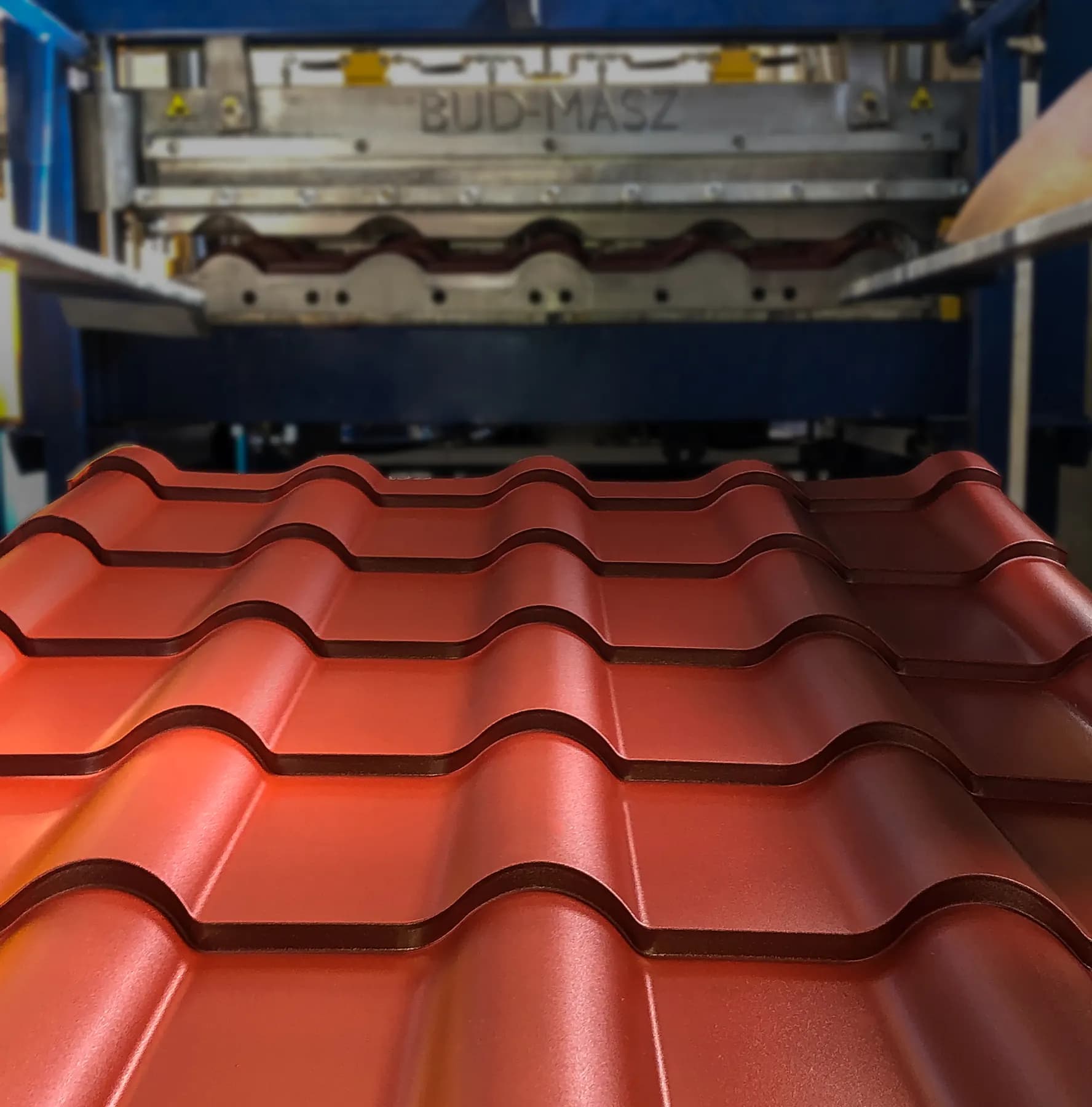 Red metal tile sheet leaving the roll-forming machine