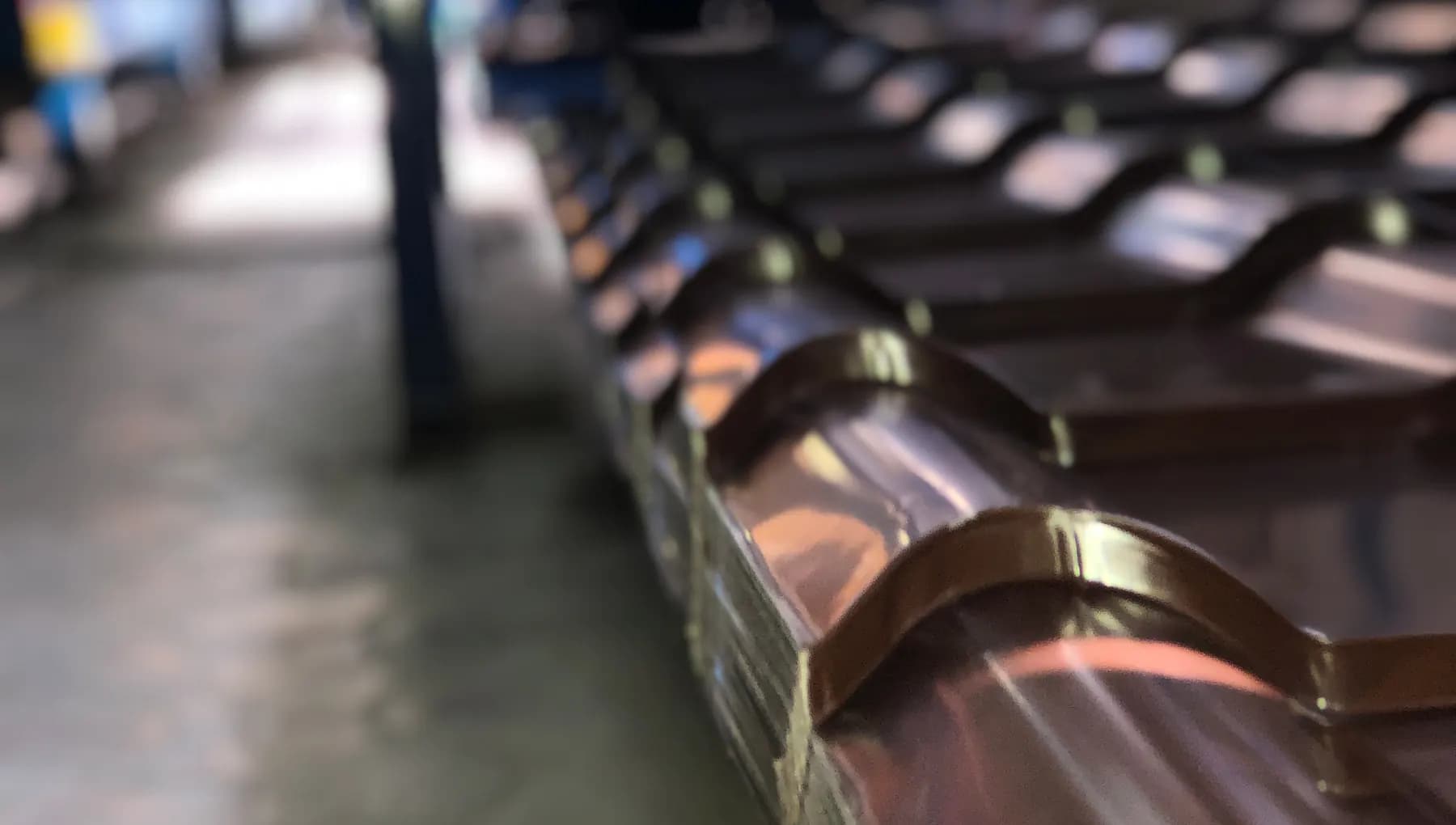 Stacks of freshly formed brown metal tile in the production hall, background out of focus