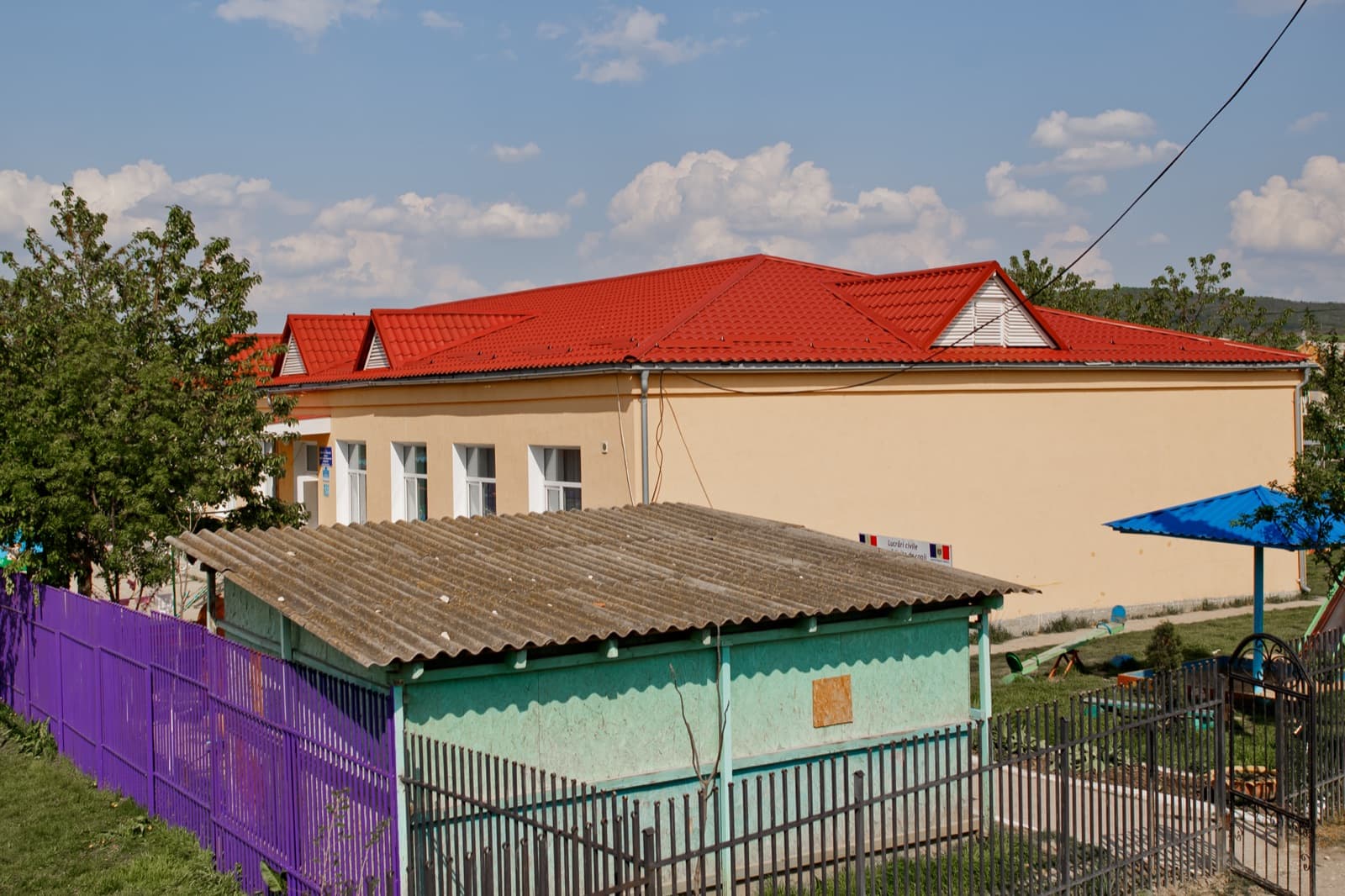 Acoperiș cu profil metalic roșu pe o clădire locală