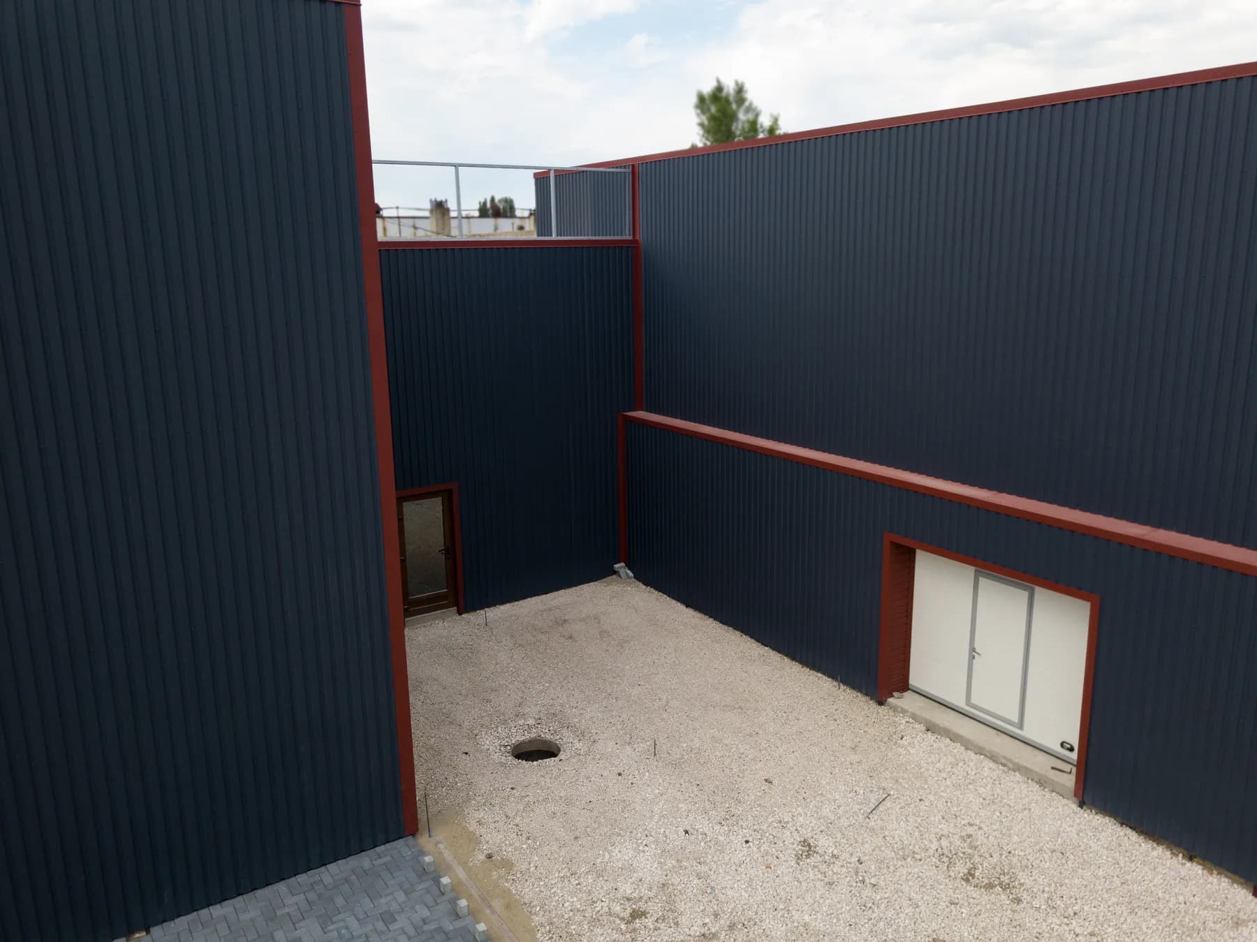 Curtea interioară a fabricii Europrofill: pereți din tablă cutată H-20 în RAL 7016 cu colțare, capace de atic, lăcrimar și ancadramente de ușă RAL 3005.