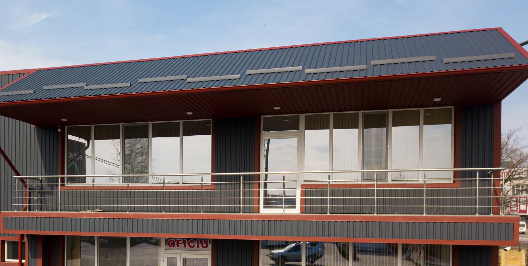 Biroul fabricii Europrofill: pereți din tablă cutată H-20 în RAL 7016, ancadramente și balcon cu borduri RAL 3005, acoperiș din tablă H-20 cu parazăpezi.